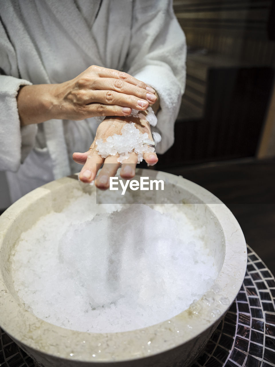 Midsection of senior woman rubbing ice on hands at spa