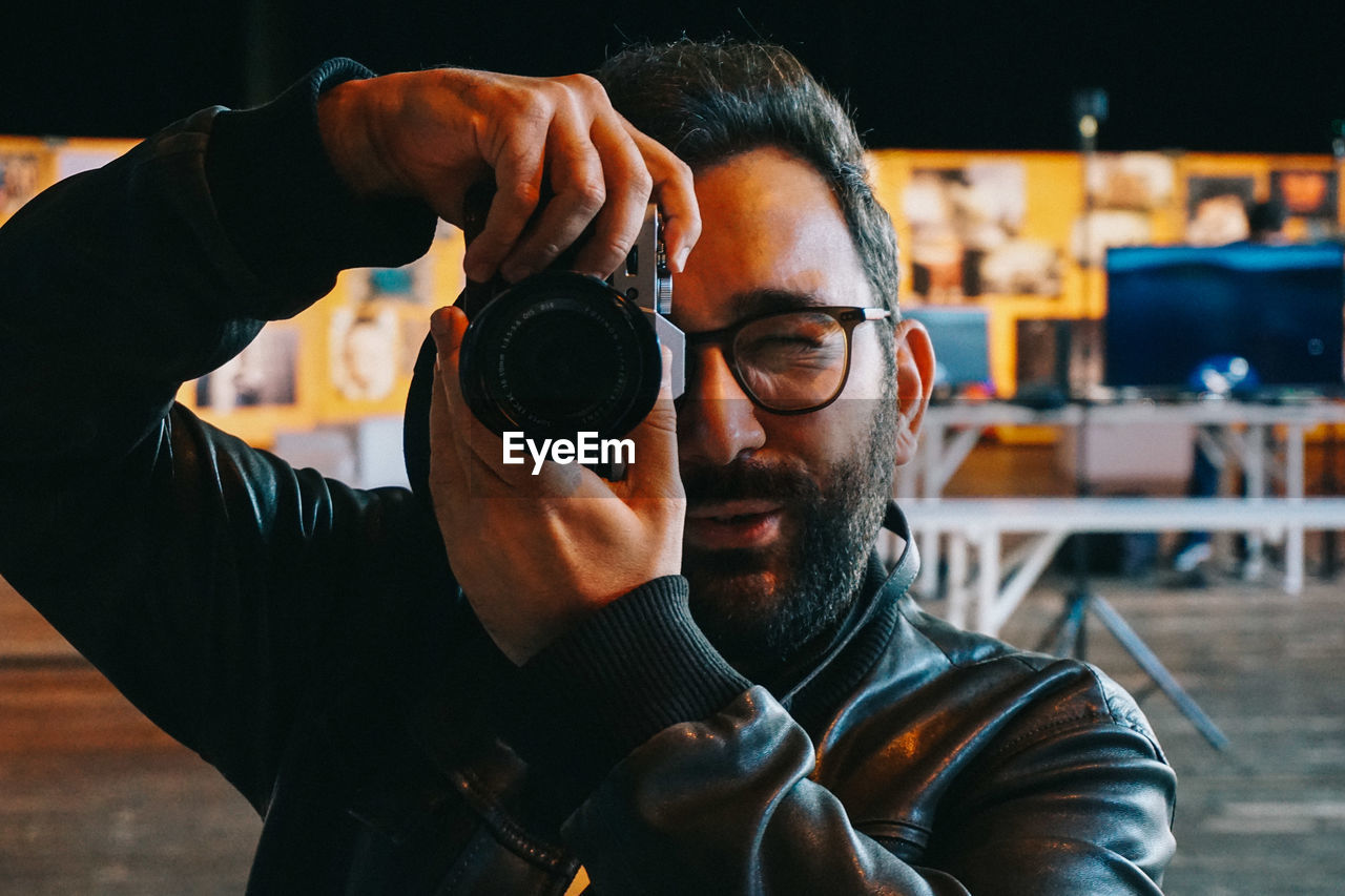 CLOSE-UP PORTRAIT OF MAN HOLDING CAMERA