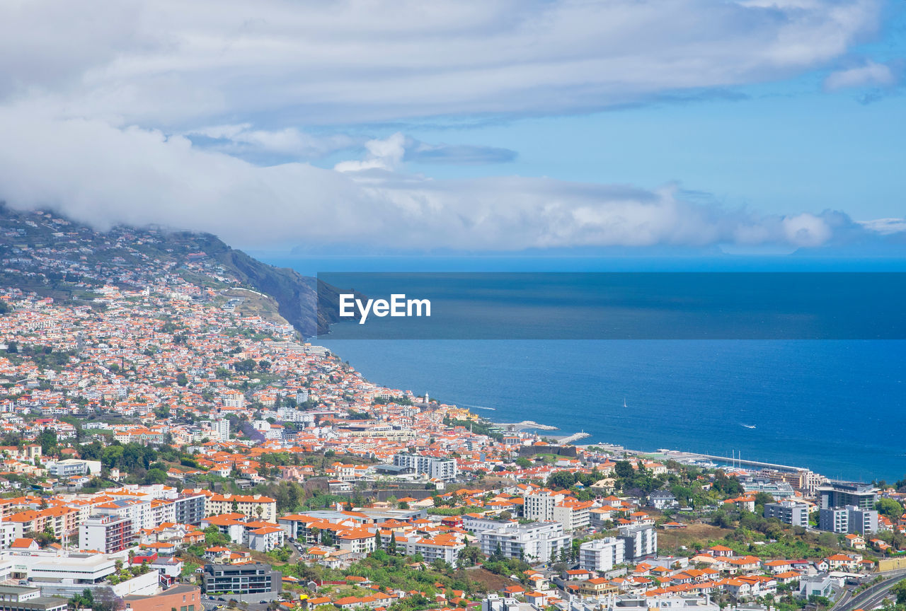 HIGH ANGLE VIEW OF BUILDINGS BY SEA AGAINST SKY