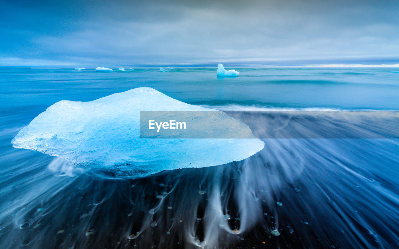 Scenic view of glacier on sea against blue sky