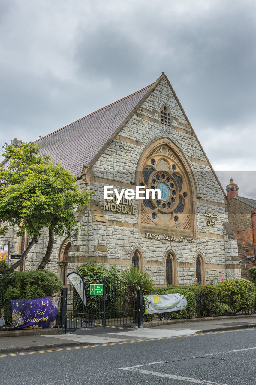 architecture, built structure, building exterior, cloud, religion, place of worship, building, sky, belief, plant, nature, spirituality, city, travel destinations, tree, no people, road, street, day, town, history, landmark, the past, outdoors, facade, house, transportation, catholicism