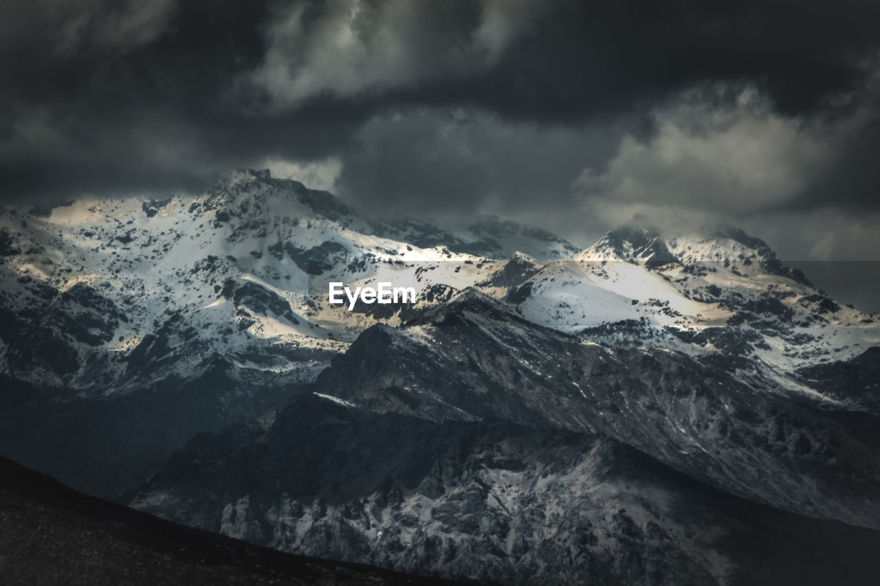 Scenic view of snowcapped mountains against cloudy sky