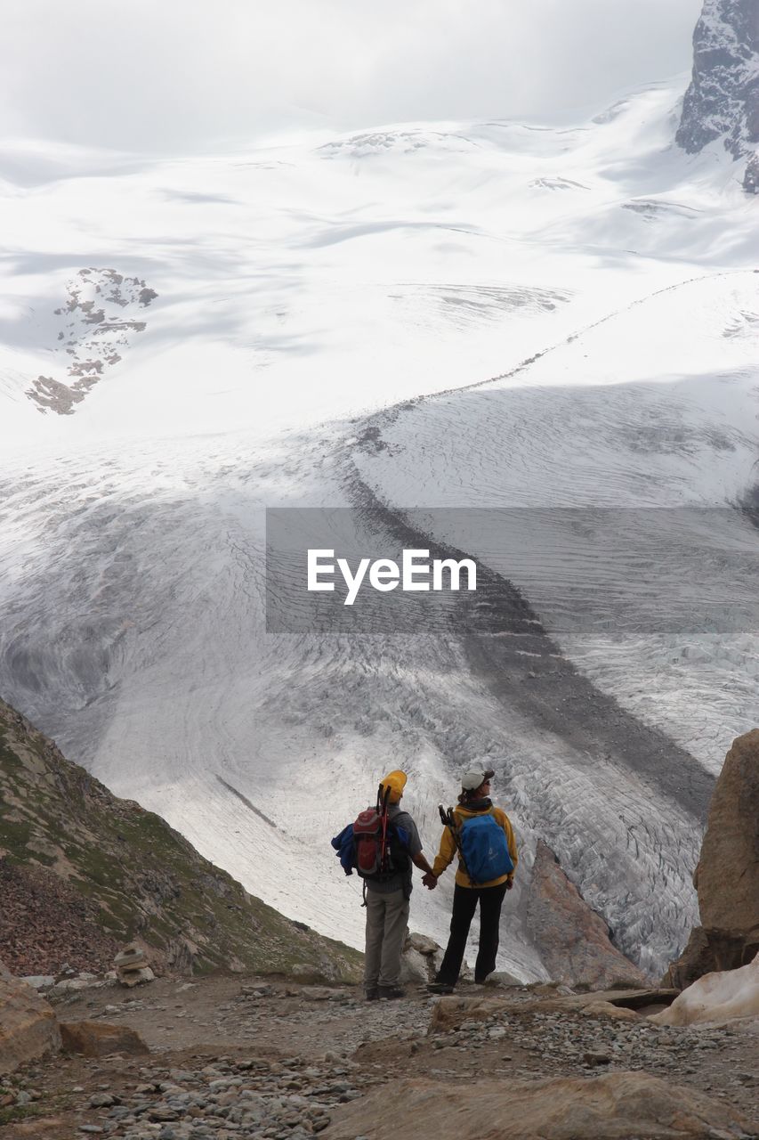 REAR VIEW OF PEOPLE STANDING ON ROCK