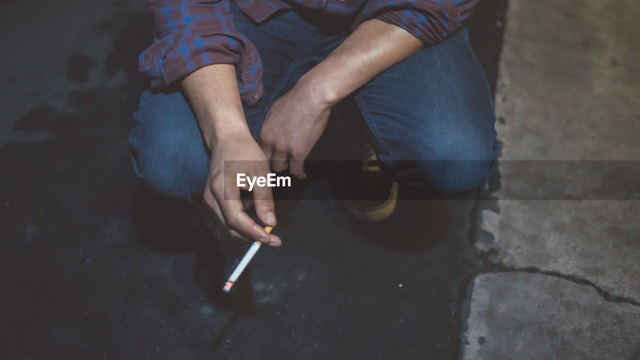Low section of man smoking cigarette