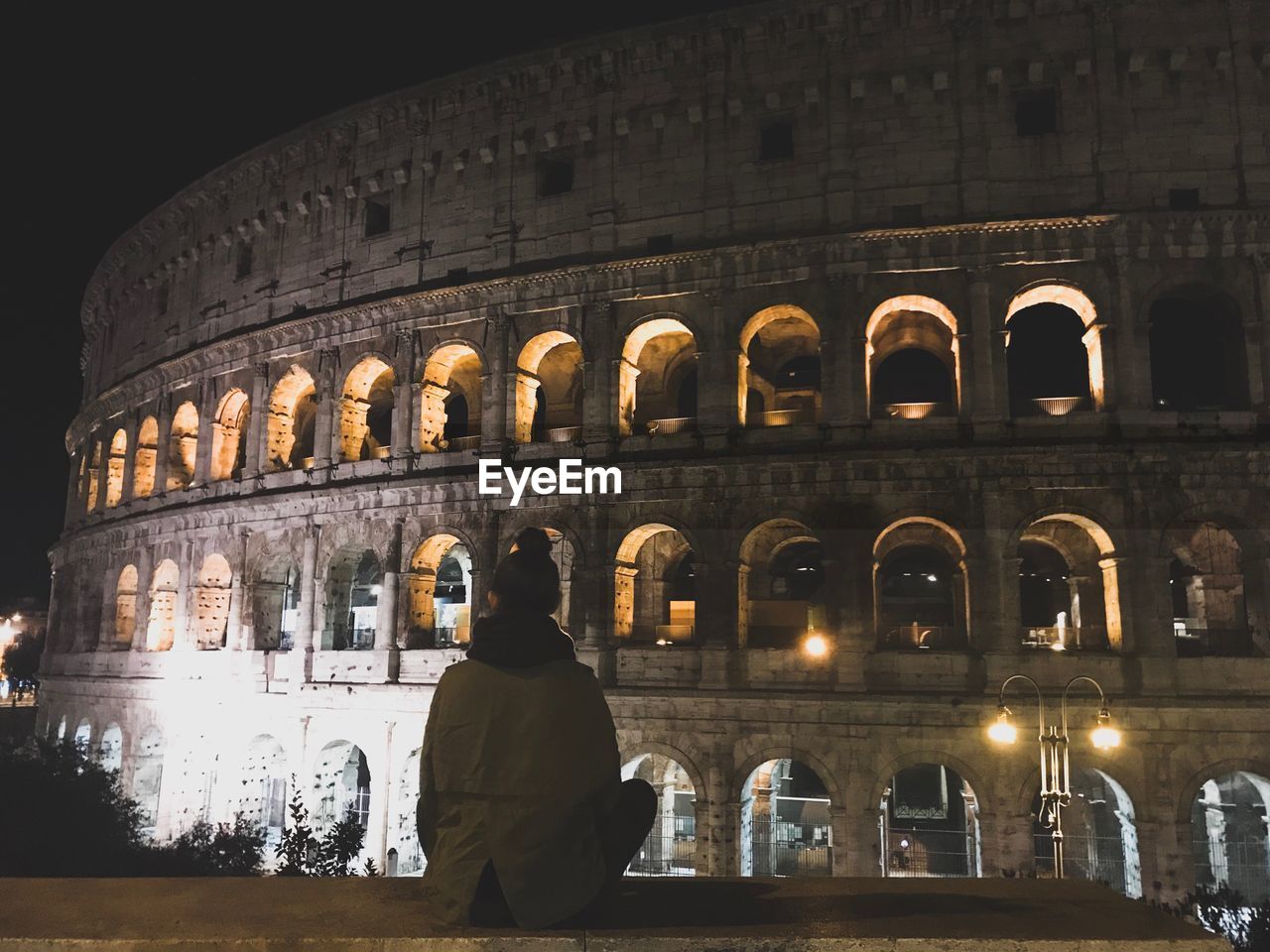 Woman sitting in front of coliseum