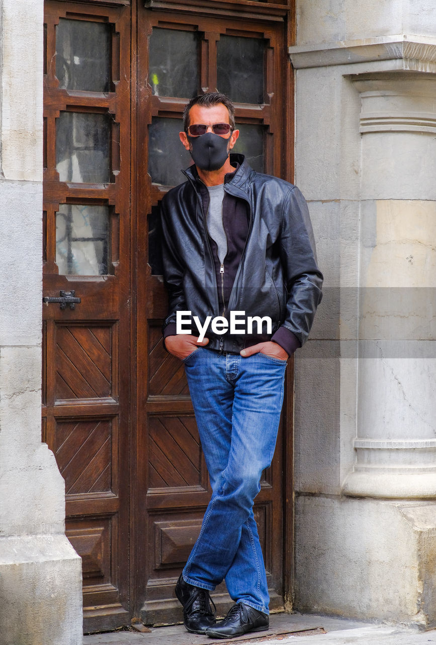 Young man wearing sunglasses standing against door