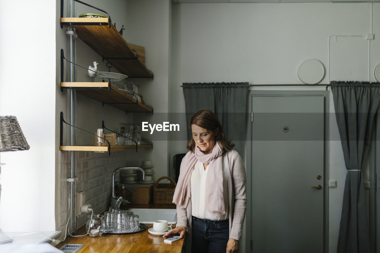 Woman in kitchen using cell phone