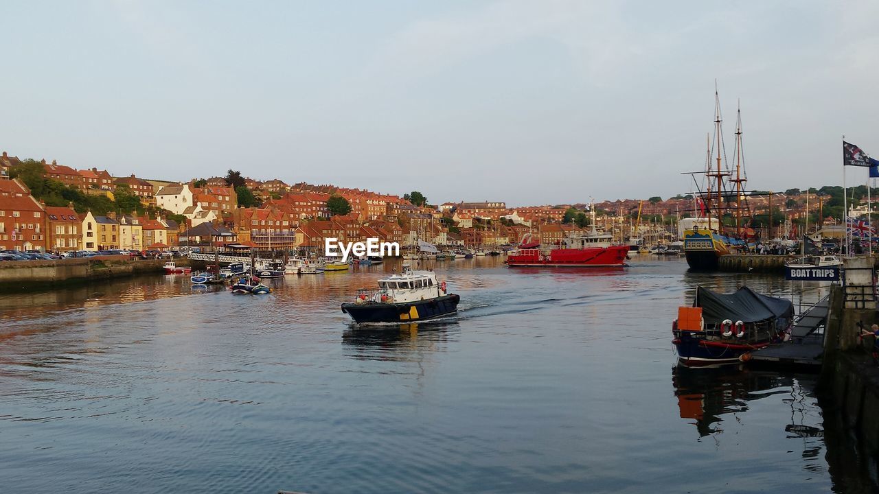 Boats moored at harbor against buildings in town