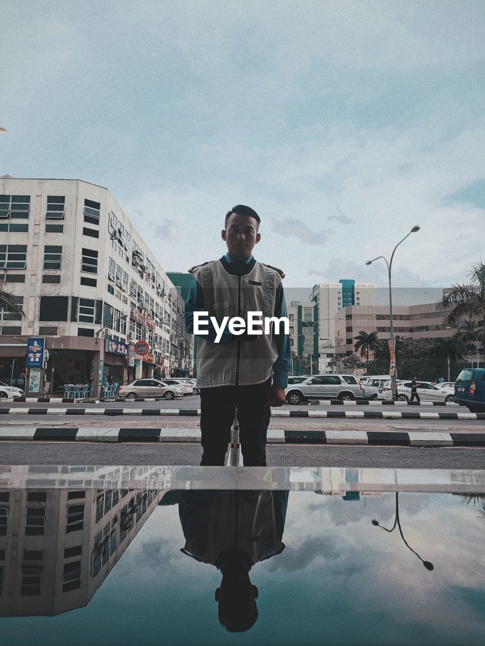 MAN STANDING BY SWIMMING POOL AGAINST SKY