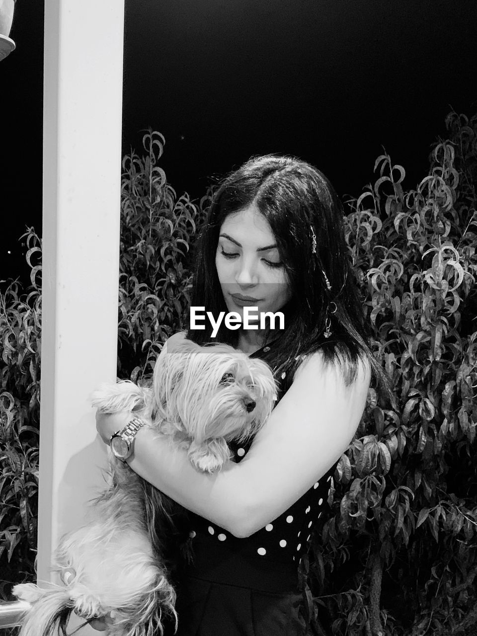 Beautiful woman carrying dog against plants