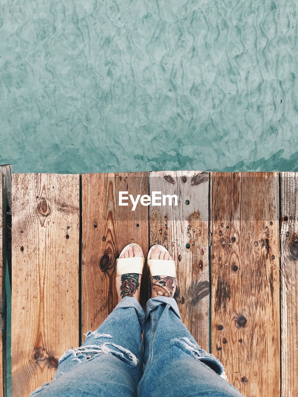 Low section of woman standing on pier over sea