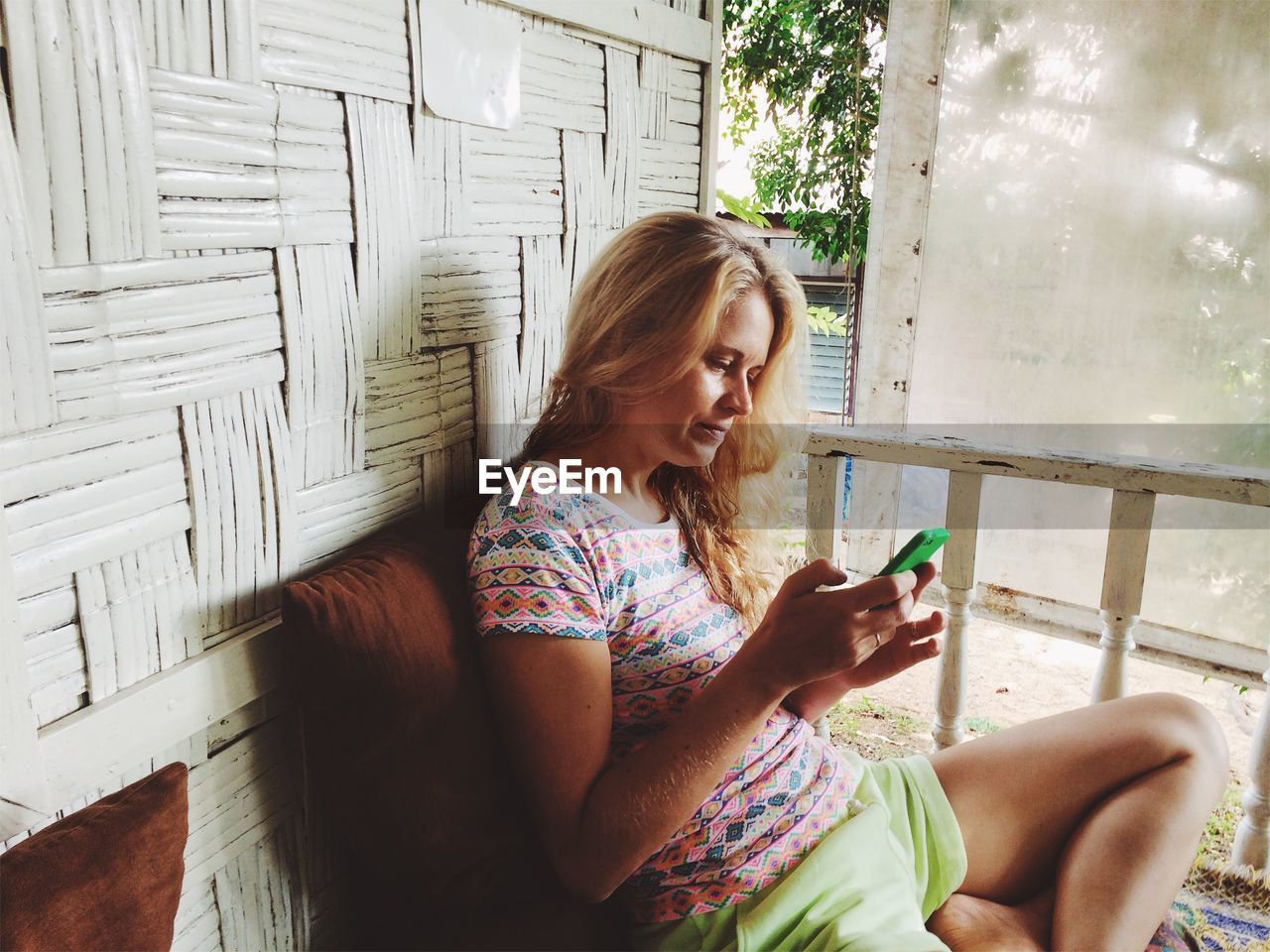 Woman using smart phone while sitting at porch