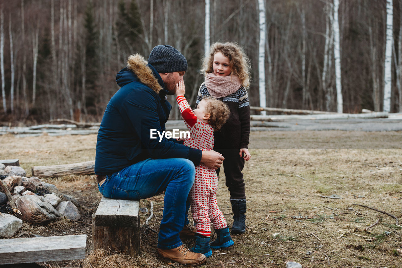 Father spending time outdoors with children in scandinavian forest