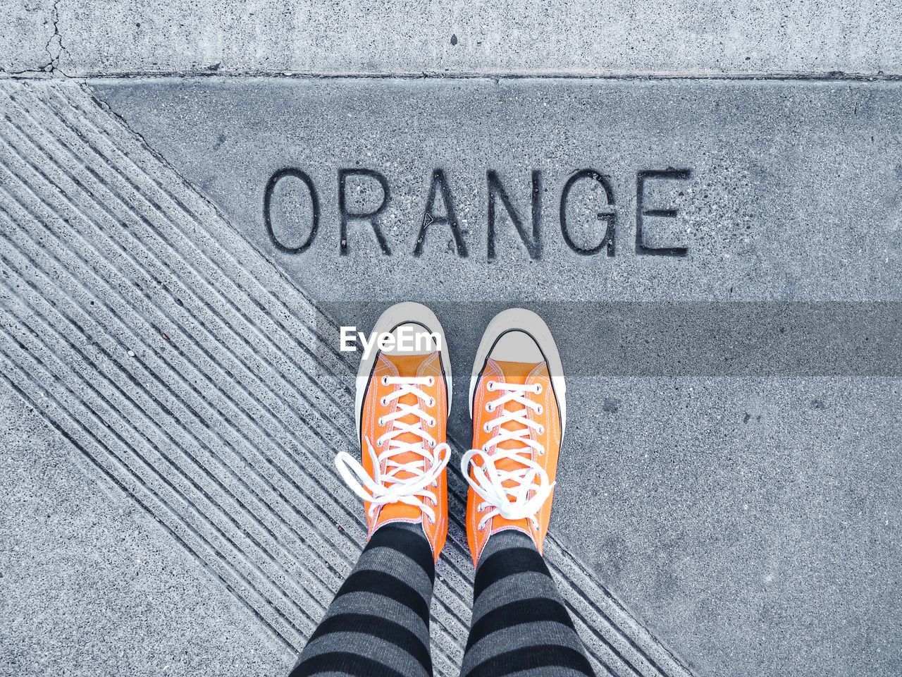 Low section of woman standing on footpath with text 