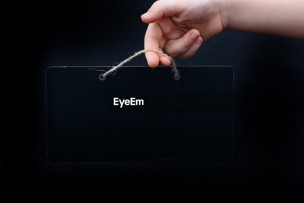 Cropped hand holding placard against black background