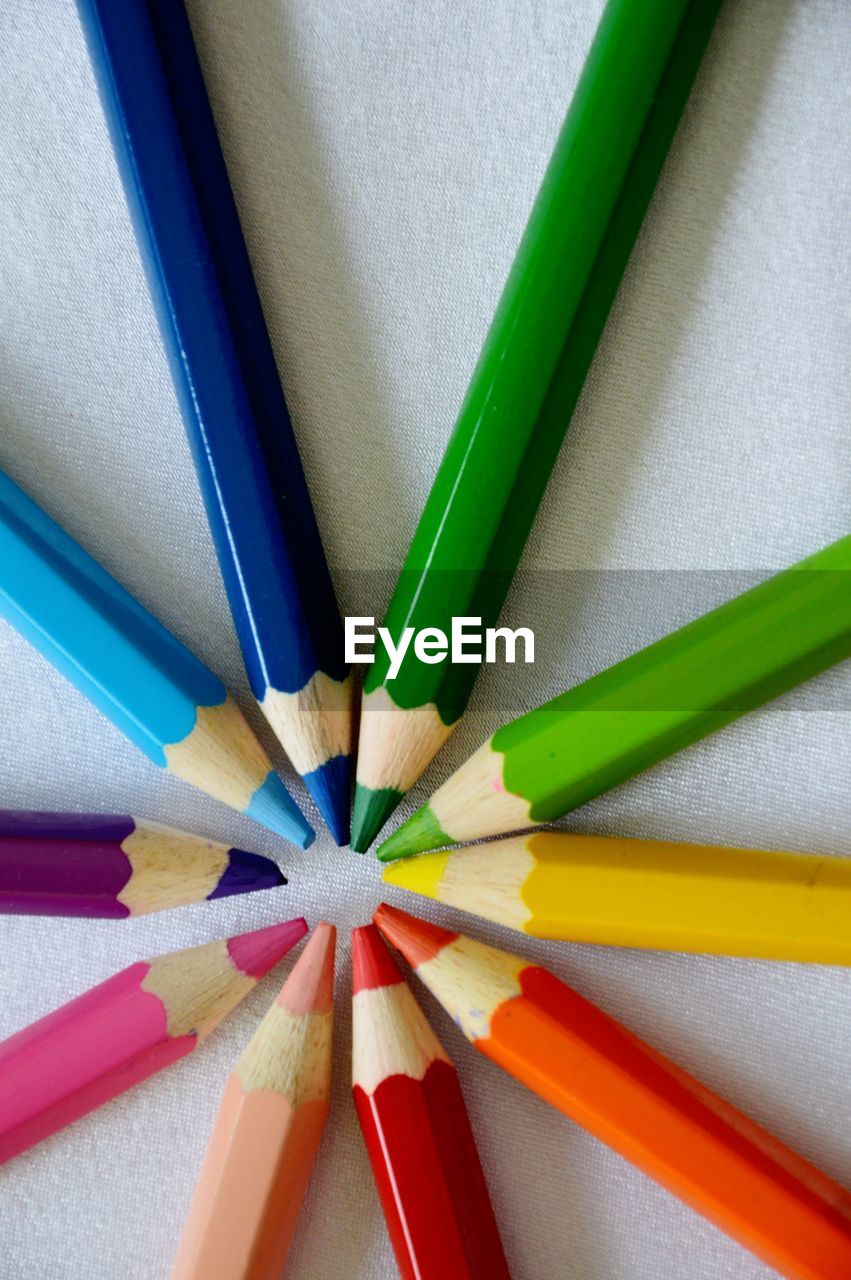 Close-up of colorful pencils arranged on white paper