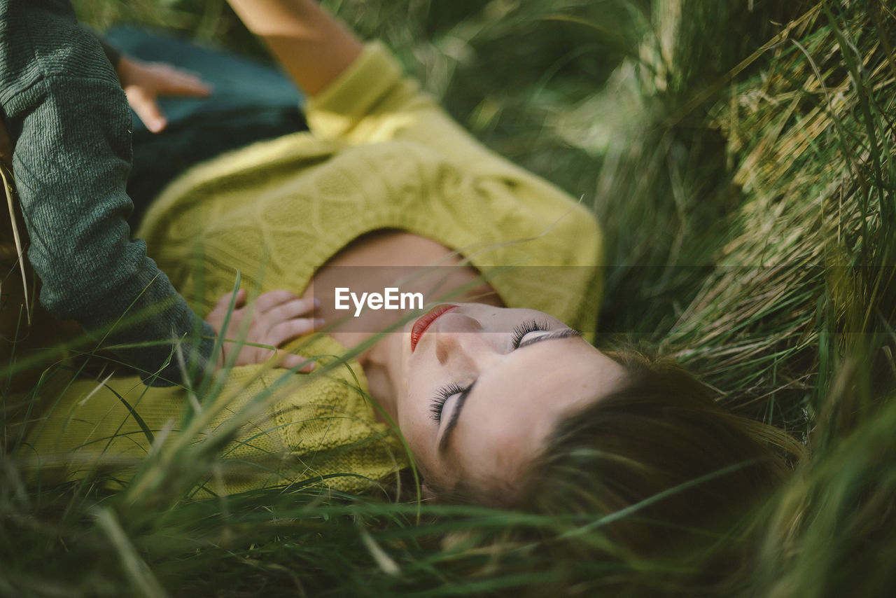 High angle view of mother with child lying on grassy field at park