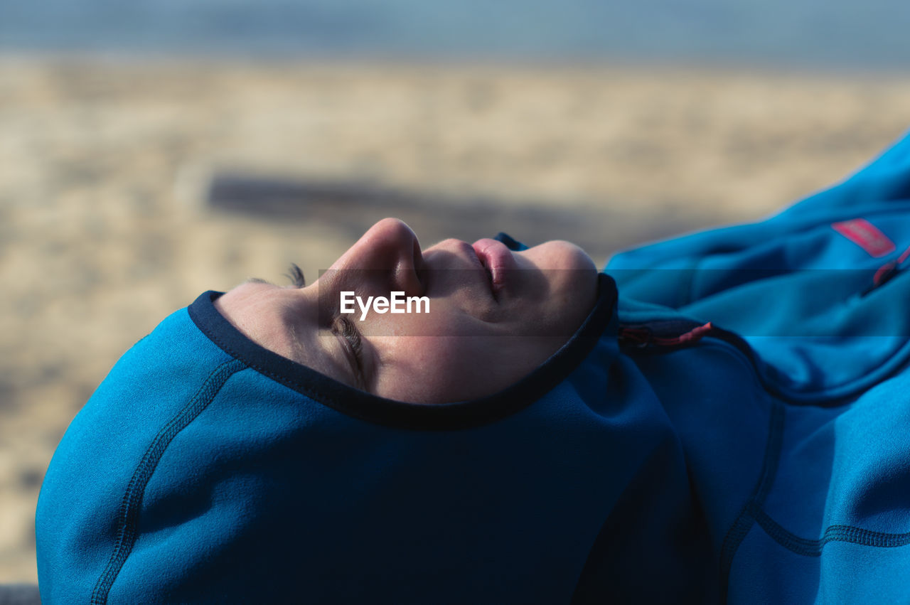 Side view of a smiling woman on the beach in outdoor clothes