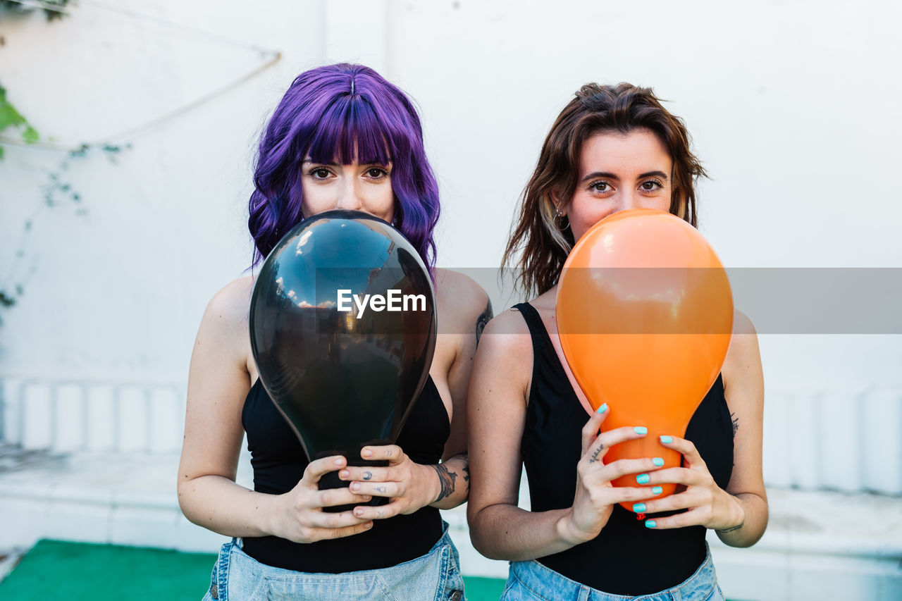 Portrait of women holding balloons while standing on land