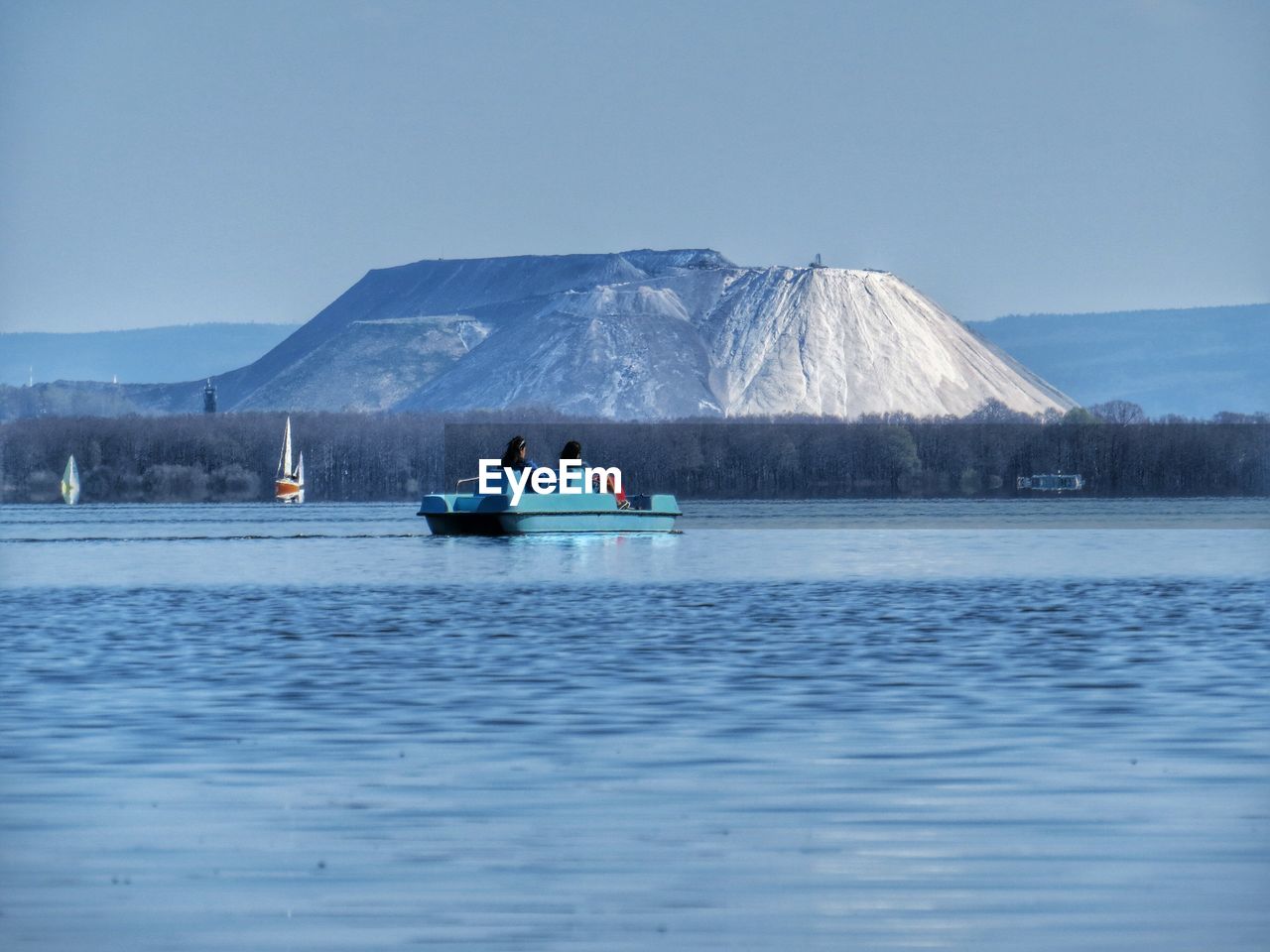 Rear view of boating in calm lake