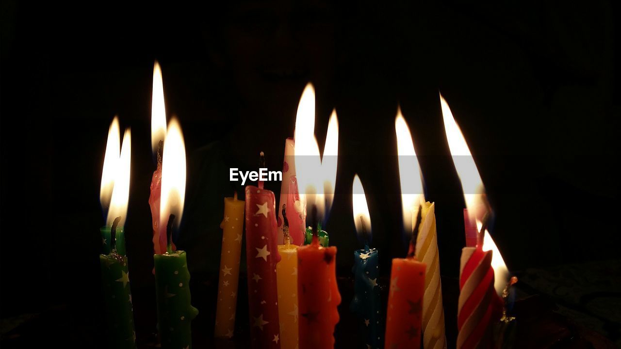 Close-up of lit birthday candles in darkroom