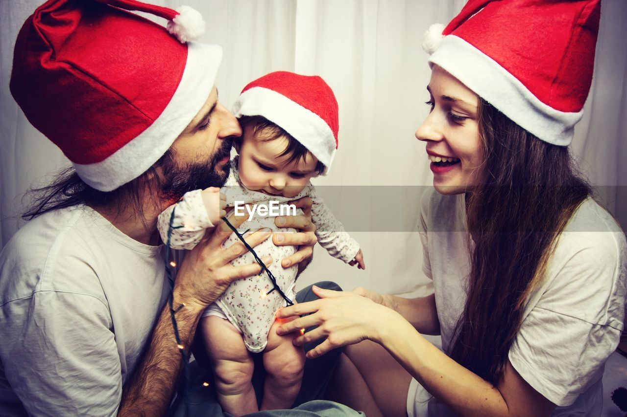 Mother looking at father holding baby girl sitting at home