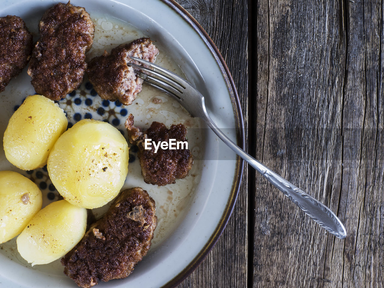 High angle view of deep fried food and potatoes in plate with fork at table