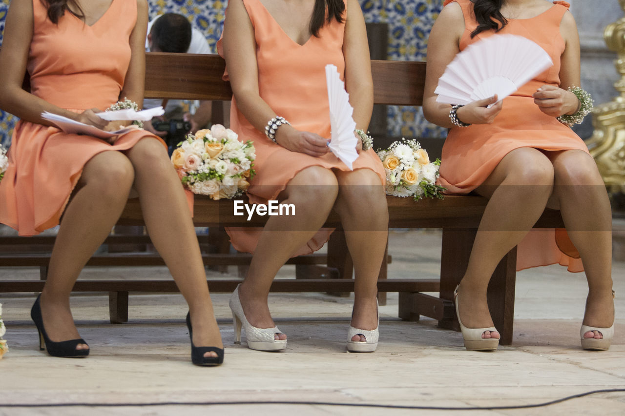 Low section of bridesmaids sitting on bench