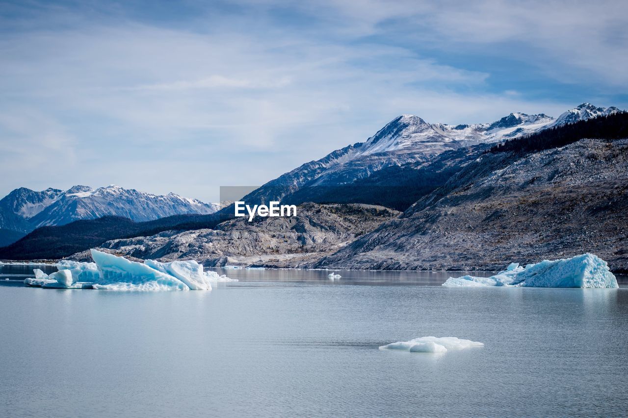 Scenic view of lake by mountains against sky during winter