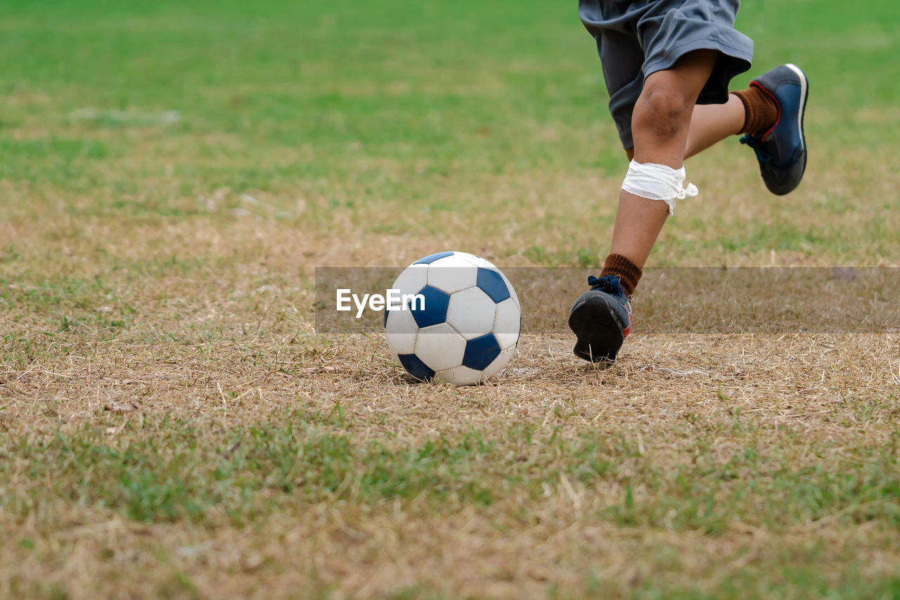 low section of man playing soccer at park