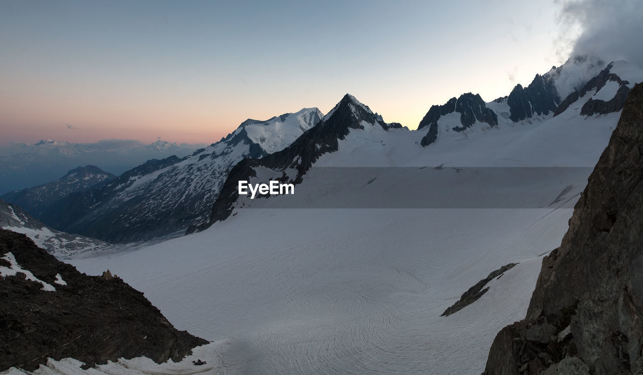 Scenic view of snowcapped mountains against sky during sunset