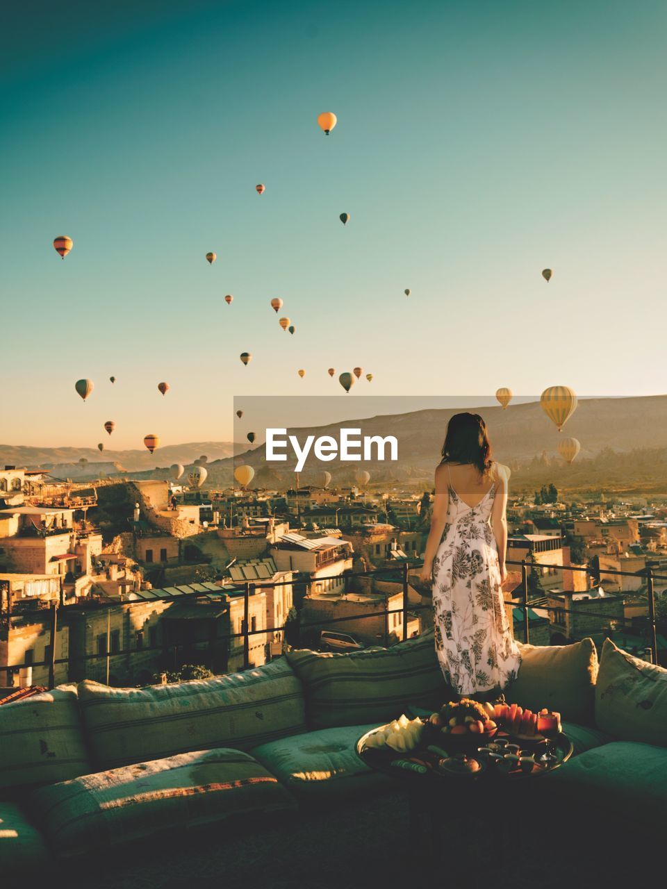 WOMAN SITTING IN CITY AGAINST SKY