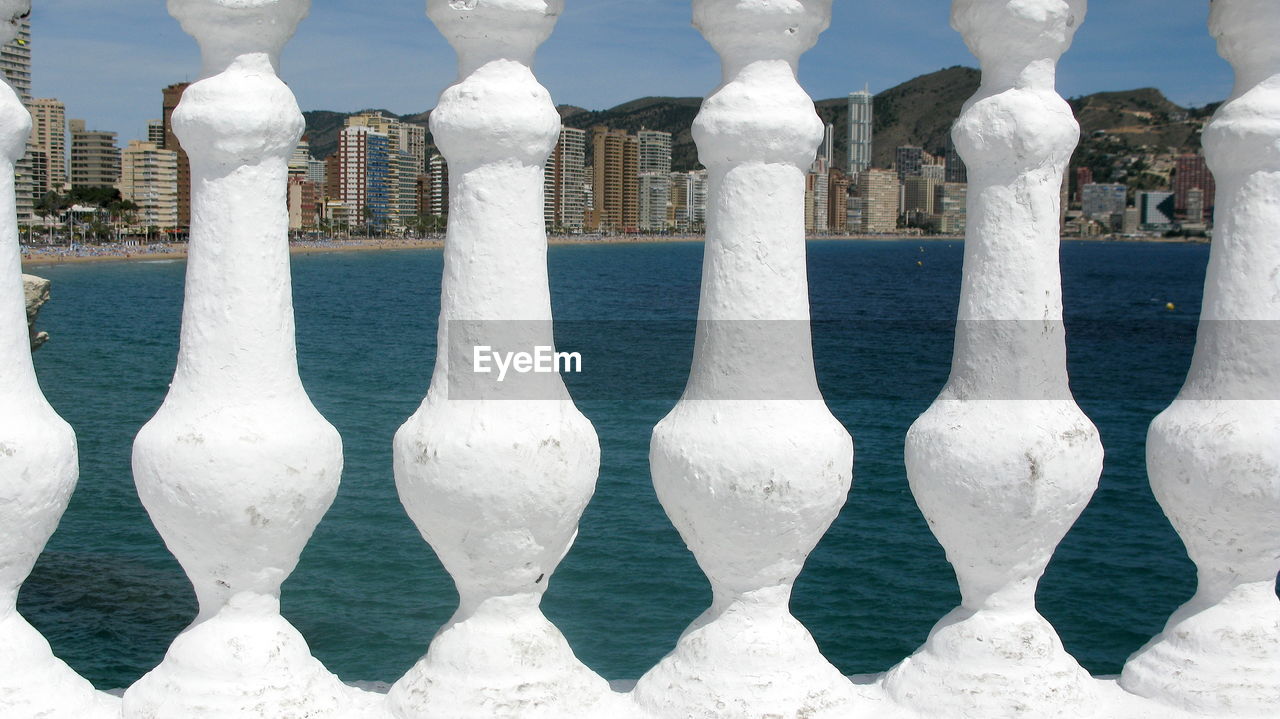 View of sea against city seen through baluster