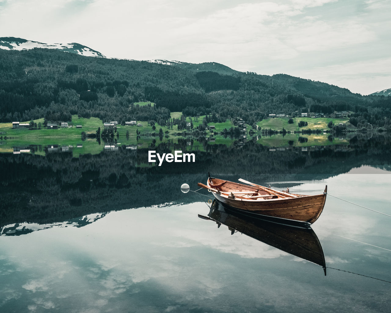 BOATS MOORED ON LAKE AGAINST SKY