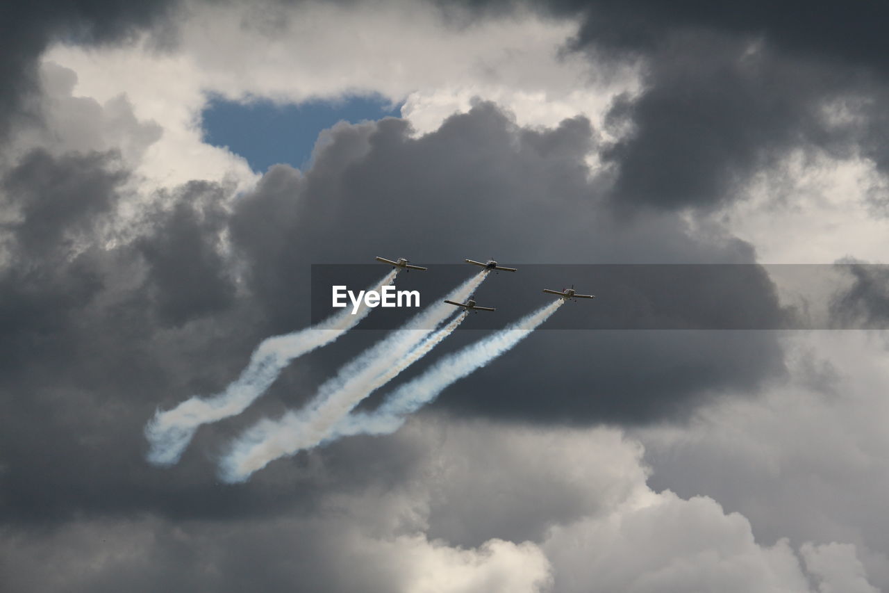 LOW ANGLE VIEW OF AIRPLANE FLYING AGAINST CLOUDY SKY