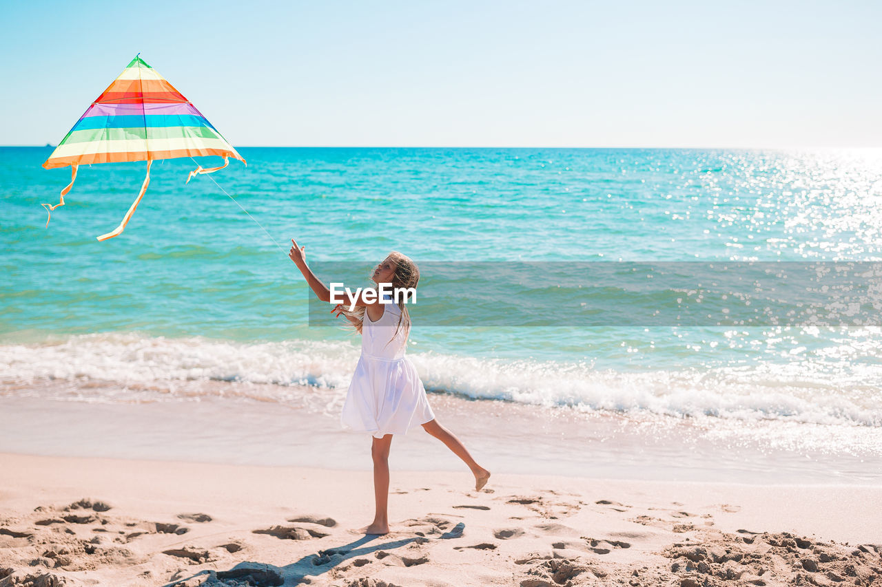 Boy standing on beach against sky