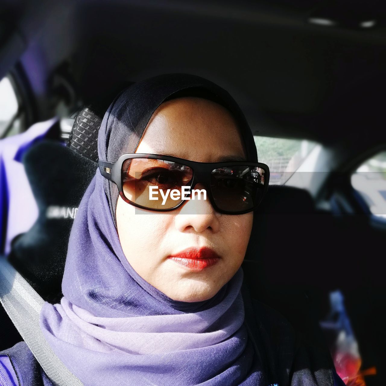 Portrait of woman wearing hijab and sunglasses while sitting in car