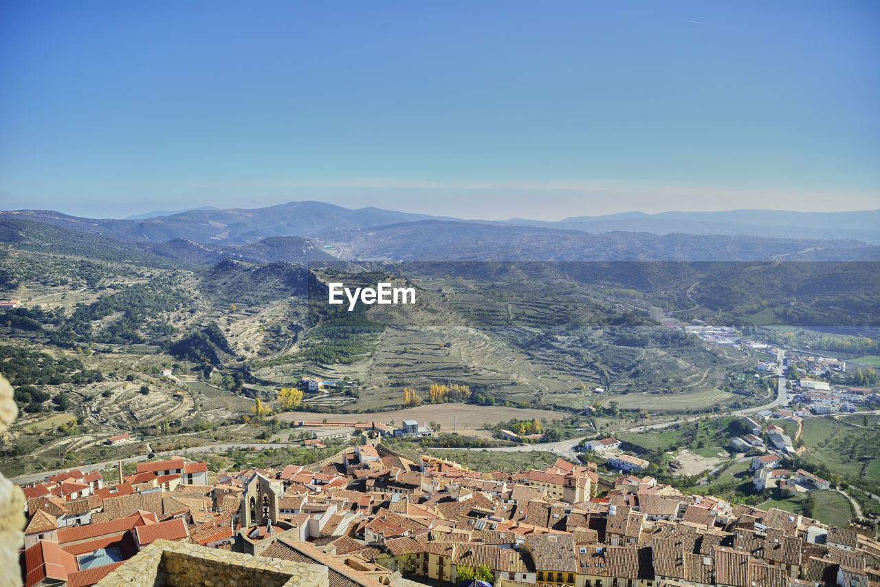 High angle view of townscape and mountains against clear blue sky