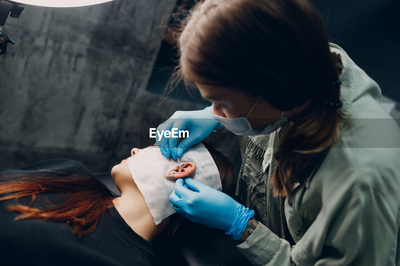 Woman piercing ear of customer
