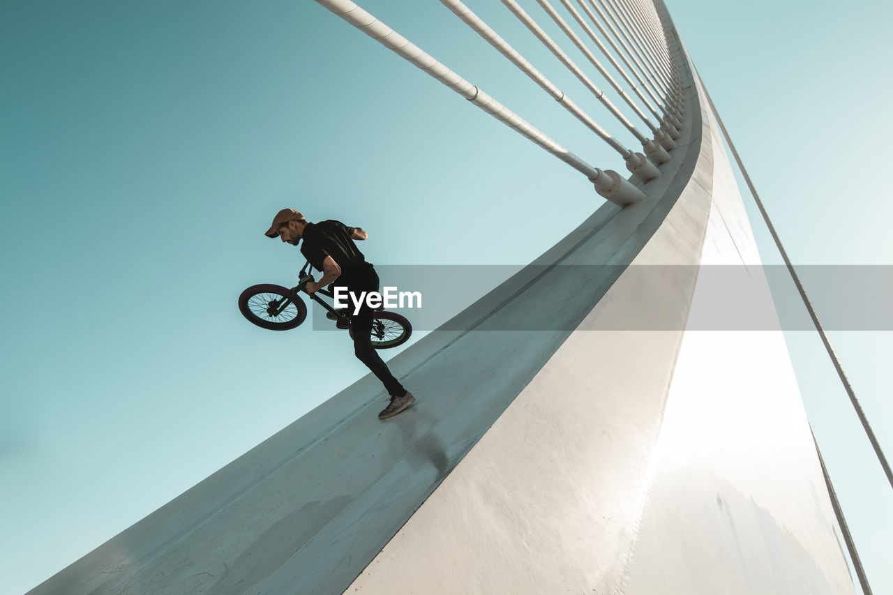 LOW ANGLE VIEW OF MAN WITH UMBRELLA ON SKY