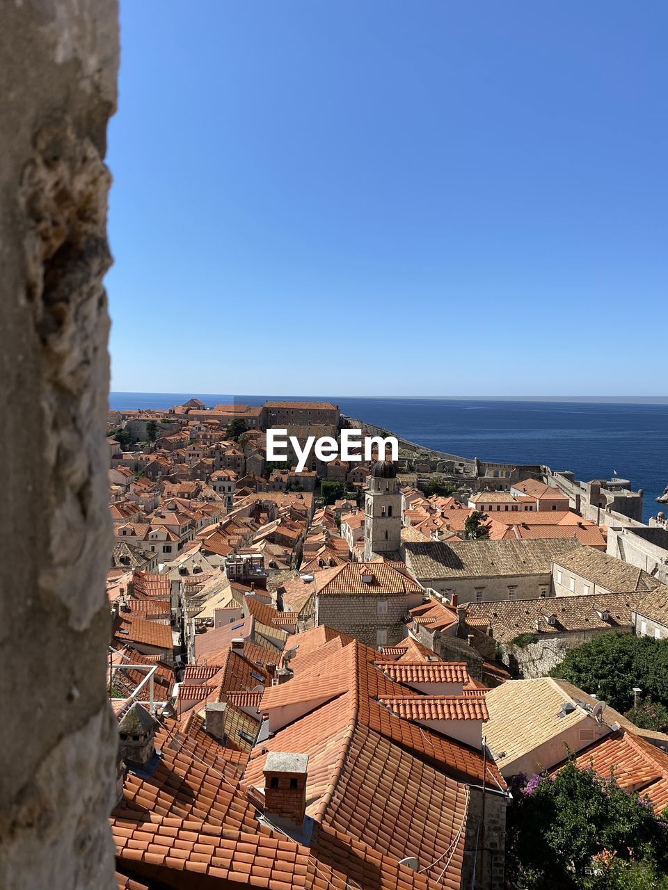 Aerial view of townscape by sea against clear blue sky