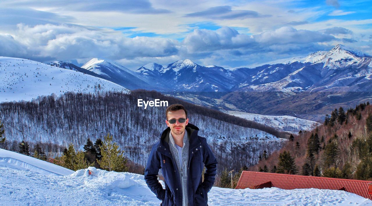 Portrait of woman in sunglasses on snowcapped mountains against sky