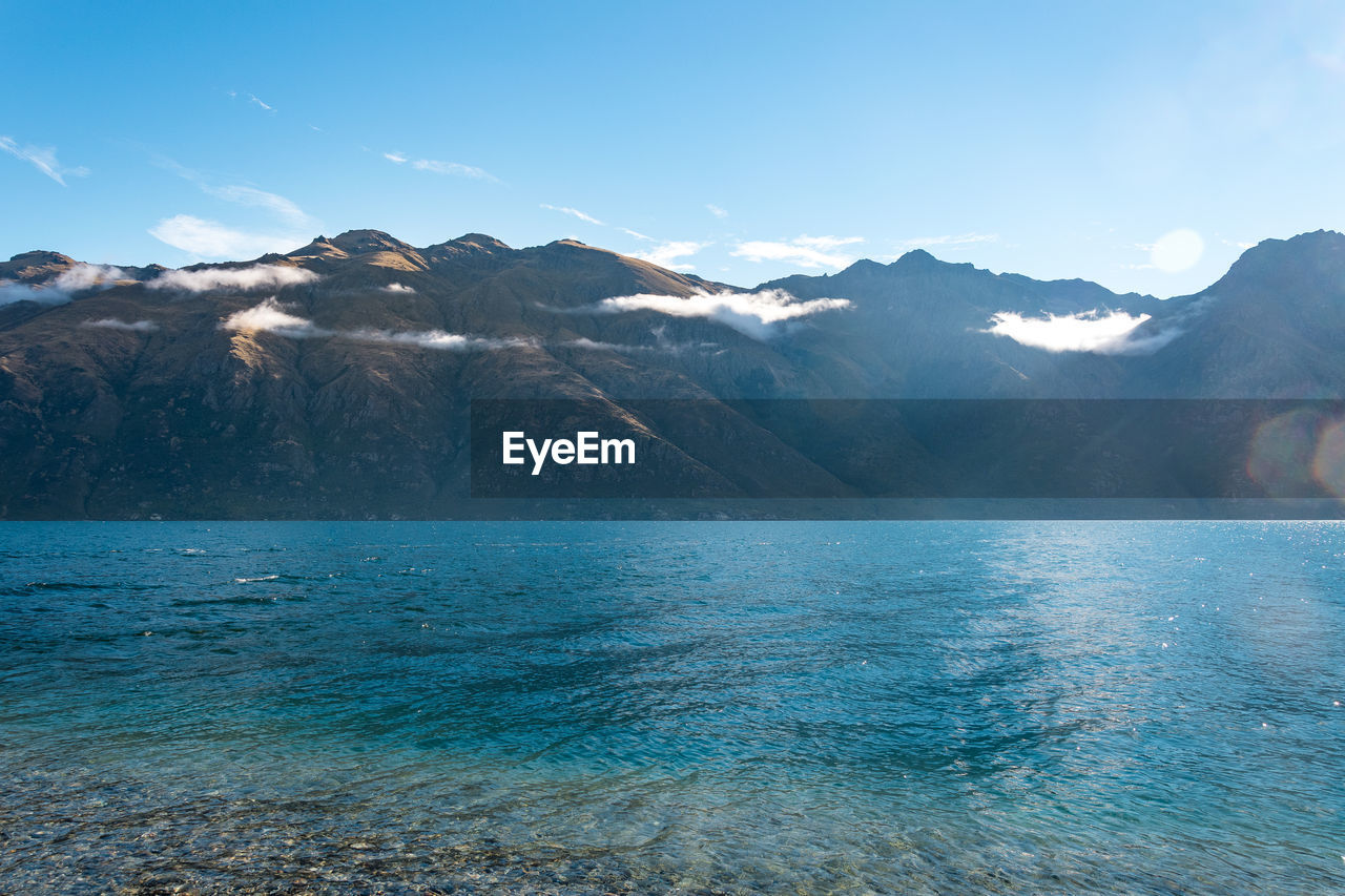 Scenic view of sea and snowcapped mountains against sky