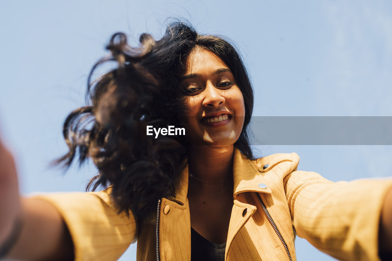 Happy young woman taking selfie on sunny day