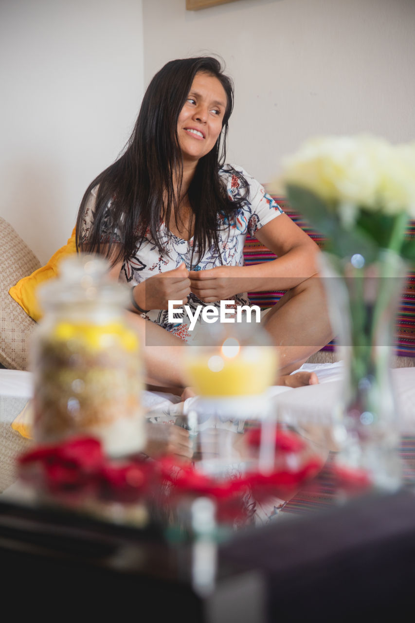 PORTRAIT OF A SMILING YOUNG WOMAN AT TABLE