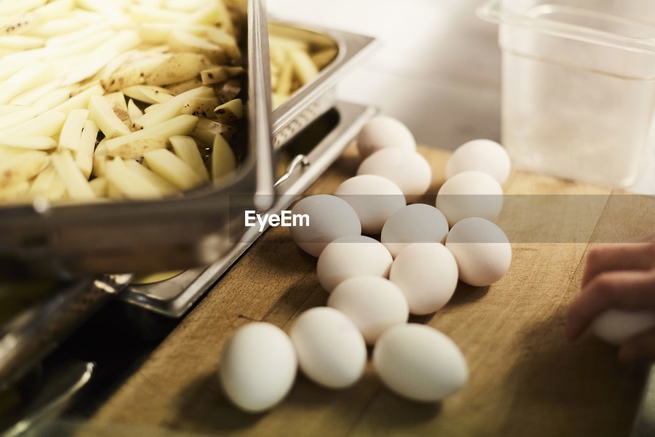 High angle view of eggs and potato slices on counter in commercial kitchen