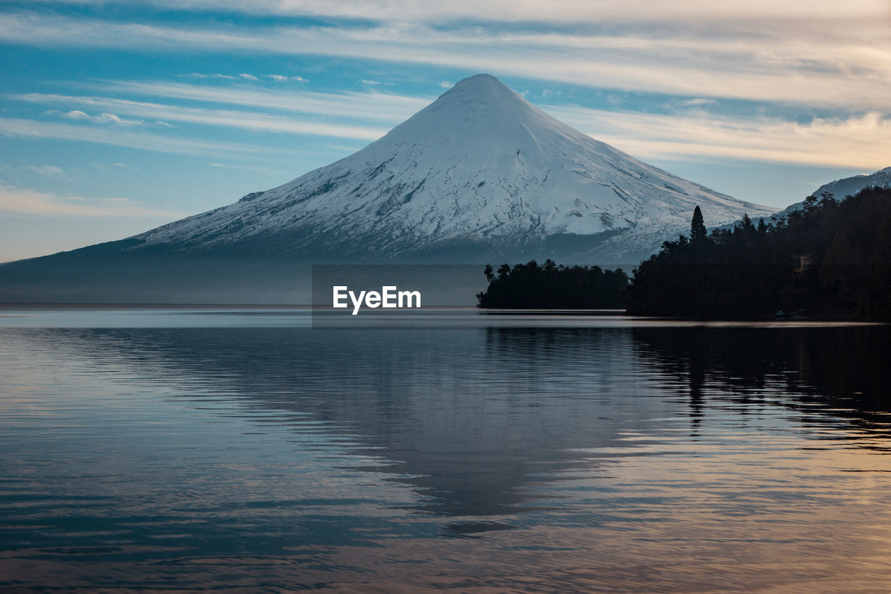 Scenic view of lake by snowcapped mountains against sky