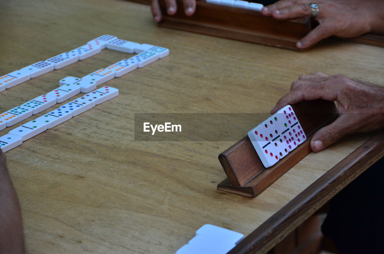 Cropped image of hands playing domino at table
