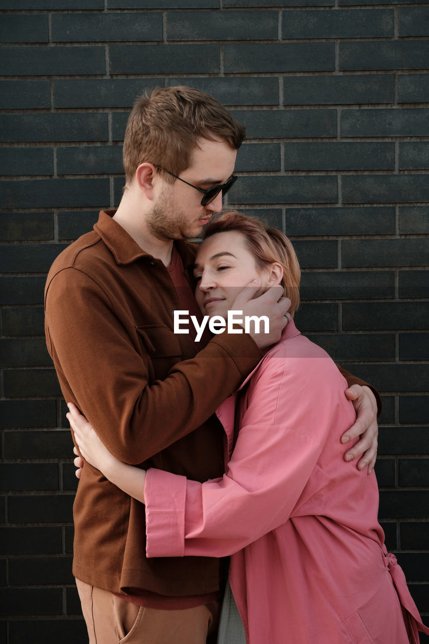 Couple hugging over dark wall. happy man and woman touching tender each other. love and romance