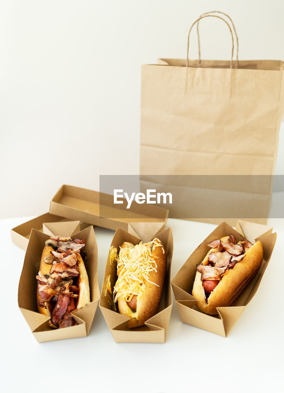 Food delivery concept. various types of hot dogs in craft packaging on the table.